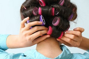 Young woman fastening red and purple velcro rollers in her hair